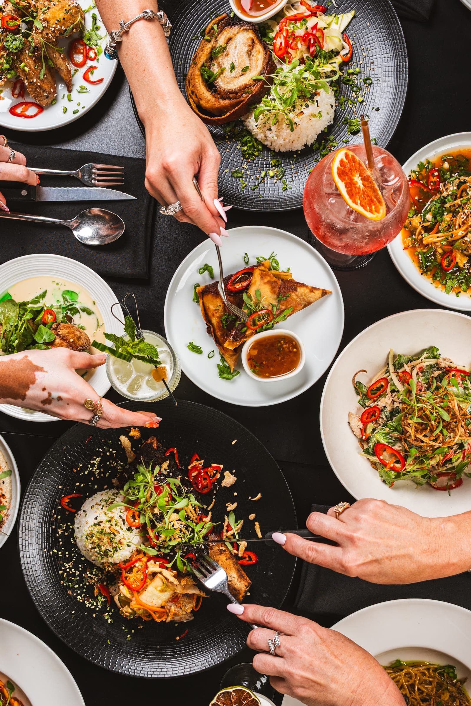 Hands reaching across a table of shared plates